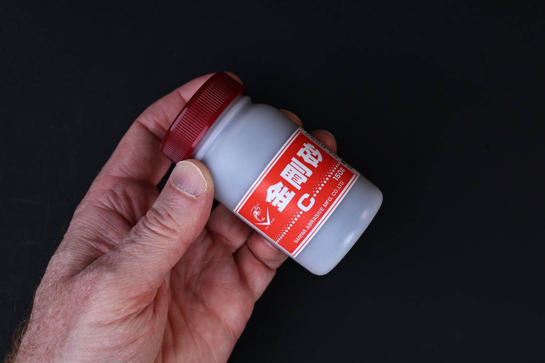 Naniwa abrasive powder 120 grit — held in hand at angle showing full red label and bottle construction