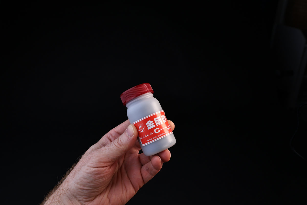 Naniwa abrasive powder 120 grit — held in hand showing full bottle size and red label detail