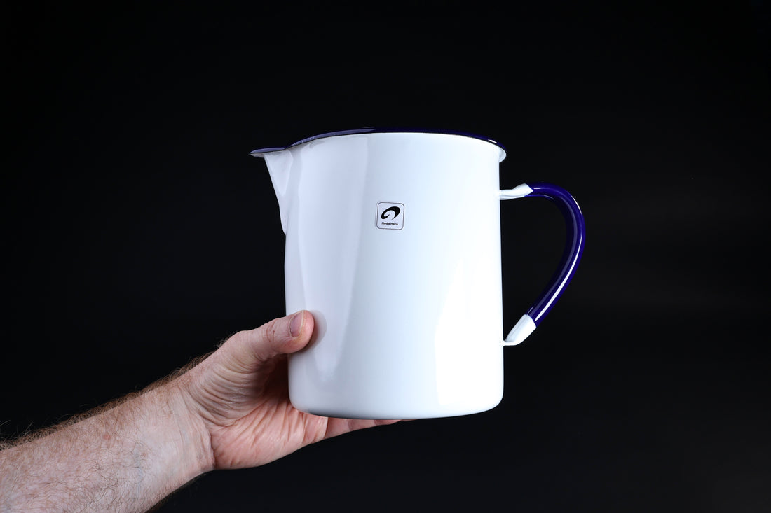 Noda Horo enamel measuring pitcher 2L — held in hand showing white enamel body and Noda Horo brand stamp