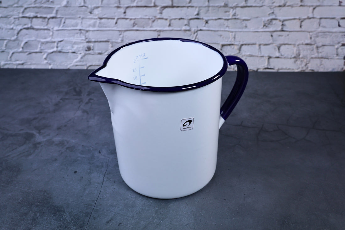 Noda Horo enamel measuring pitcher 2L — three-quarter view showing spout, blue rim, and Noda Horo logoNoda Horo enamel oil pot — full side view with lid showing white enamel body and handle
