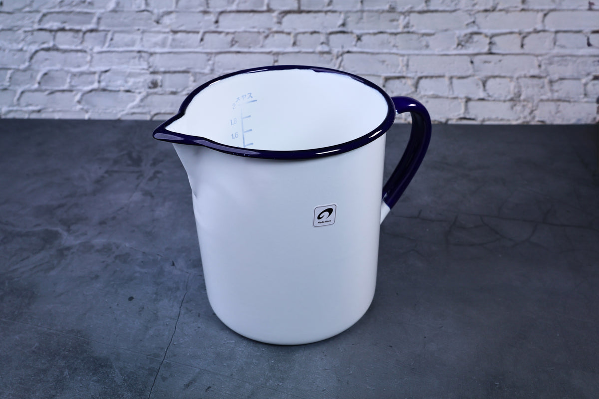 Noda Horo enamel measuring pitcher 2L — three-quarter view showing spout, blue rim, and Noda Horo logoNoda Horo enamel oil pot — full side view with lid showing white enamel body and handle
