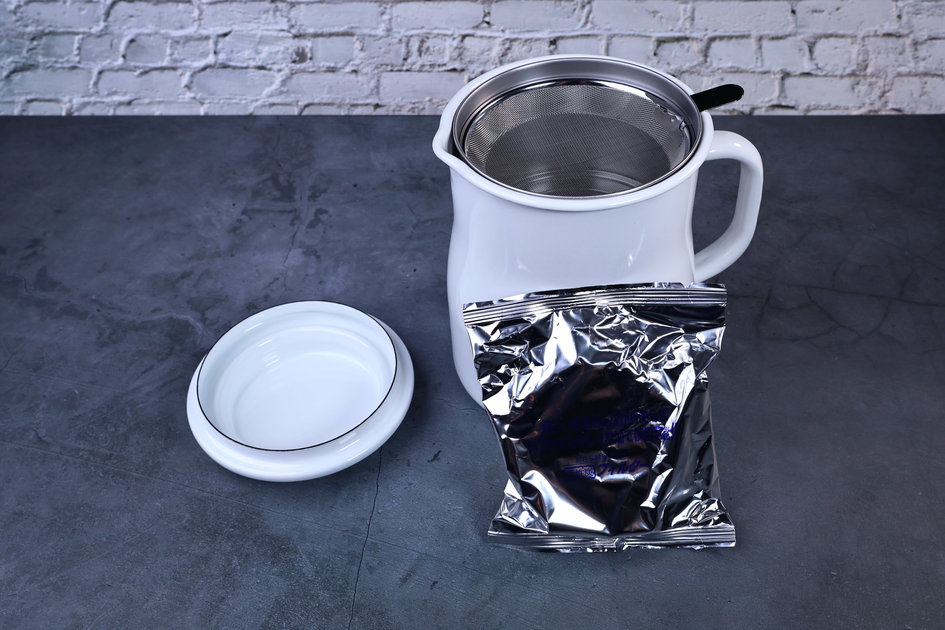 Noda Horo enamel oil pot — open showing filter and included charcoal refill packet alongside pot