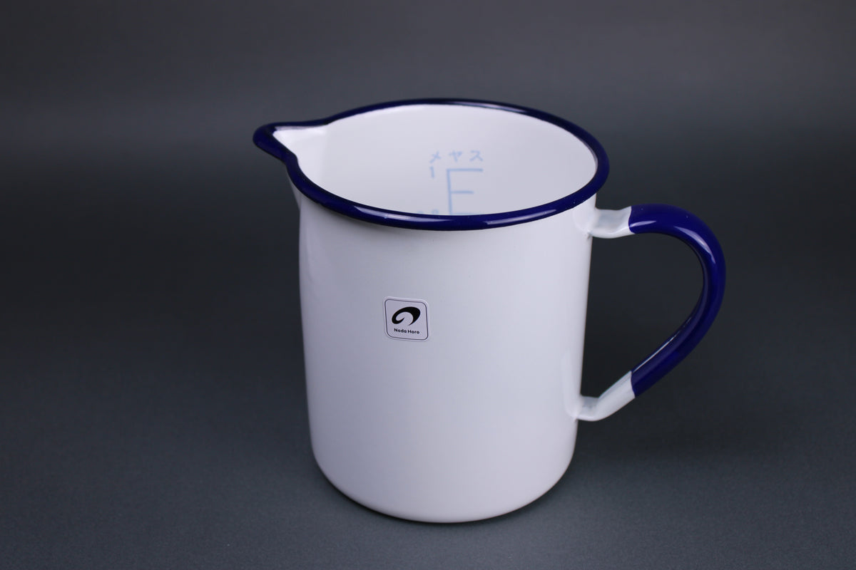 frontal view of noda horo one liter measuring cup with white glazed body navy blue glaze on the handle and the rim of the pitcher with grey background