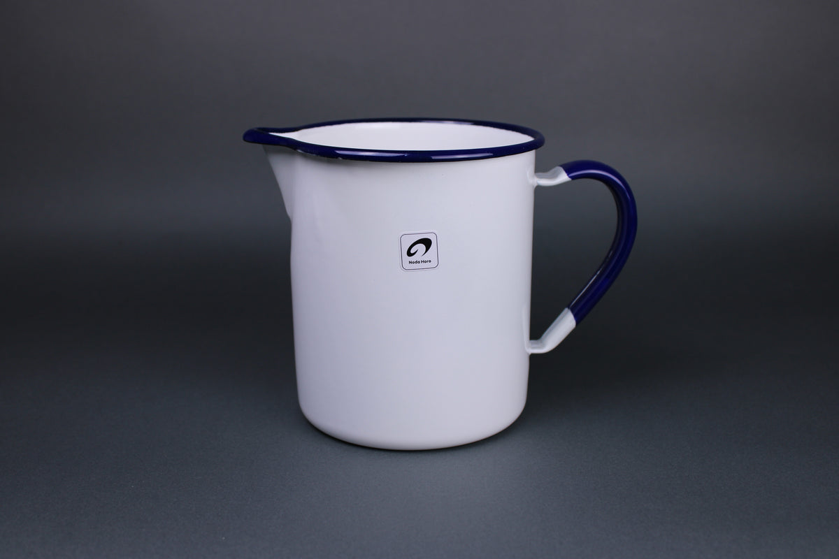 frontal image of white glazed and blue trimmed noda horo pitcher with curved rim to allow easy pouring and a stout handle with a grey background