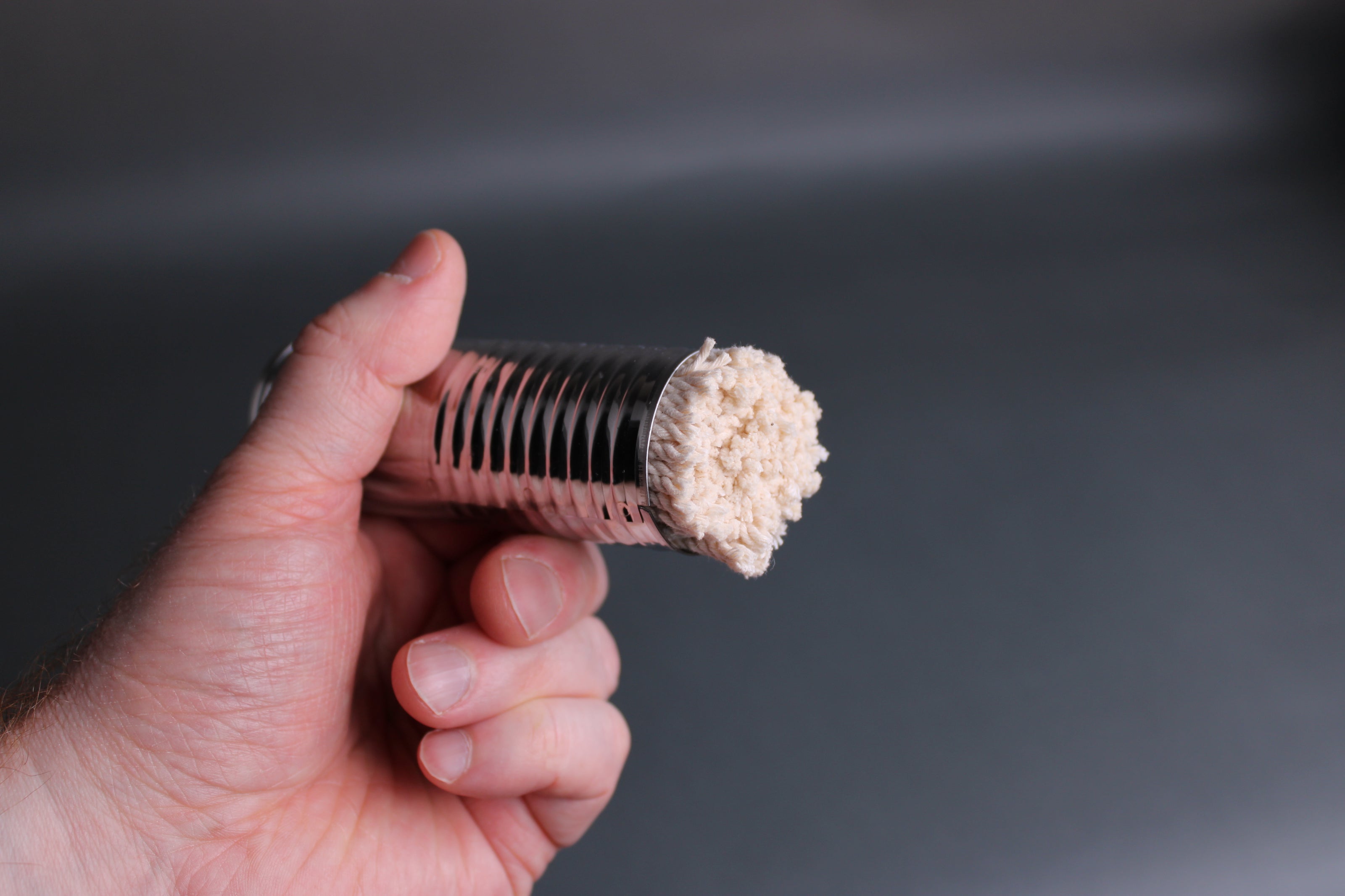 hand holding metal container with cotton brush for oiling pan by Ichiboshi metal company grey background