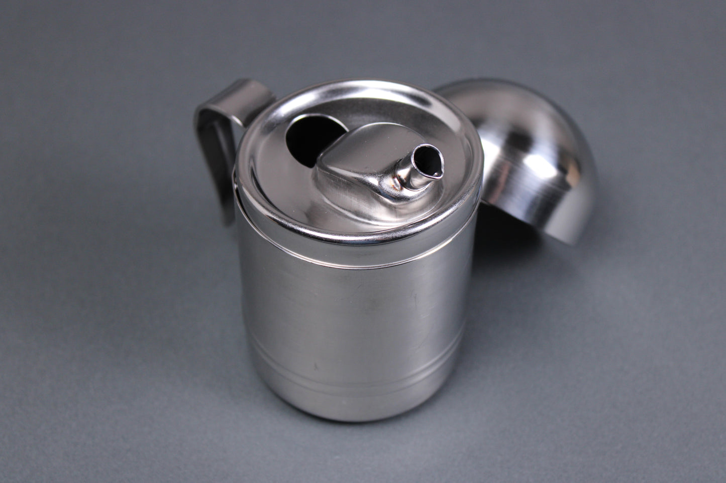 japanese stainless steel oil cruet from niigata with domed lid angled spout and grey background 
