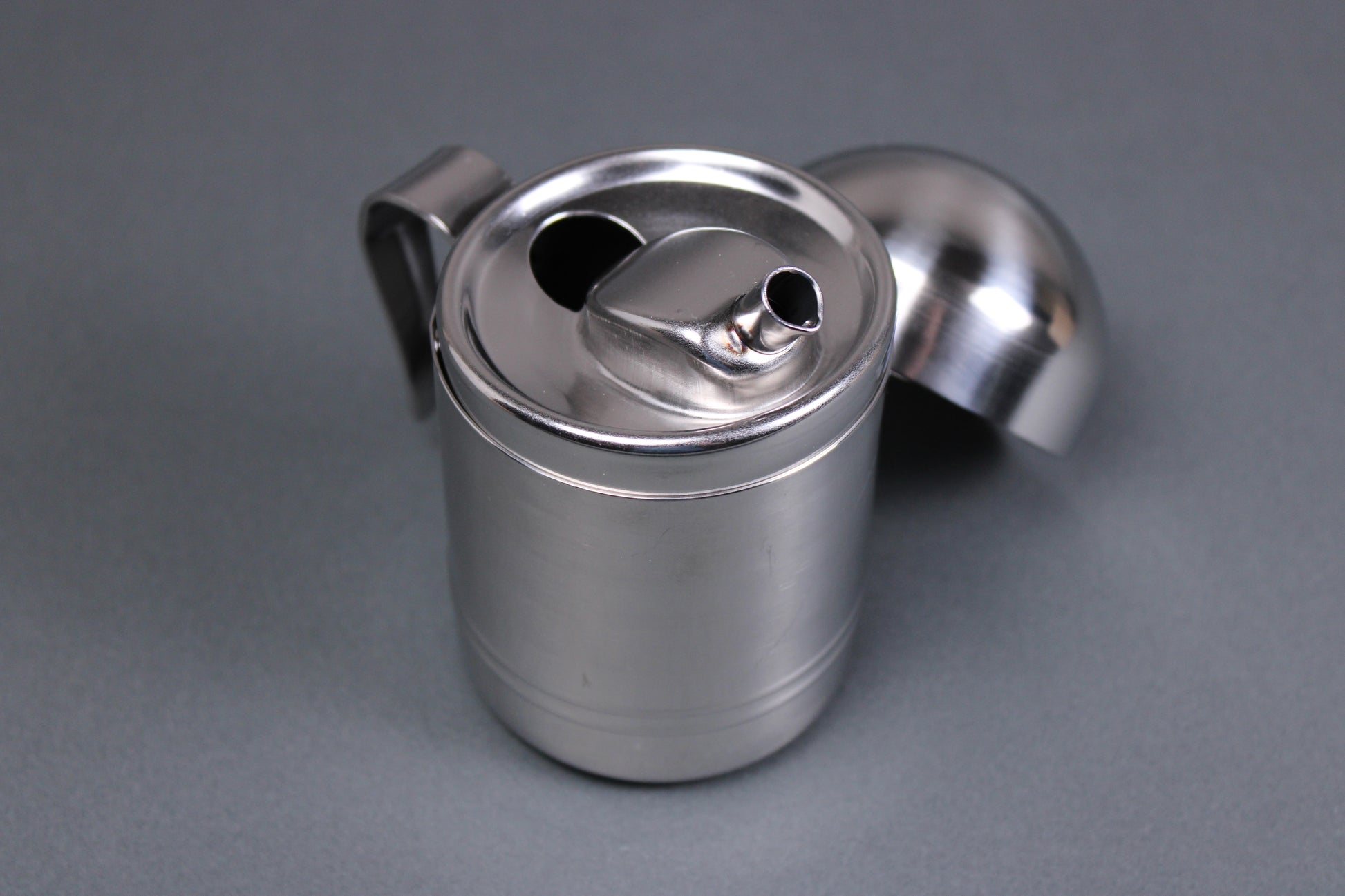 japanese stainless steel oil cruet from niigata with domed lid angled spout and grey background 