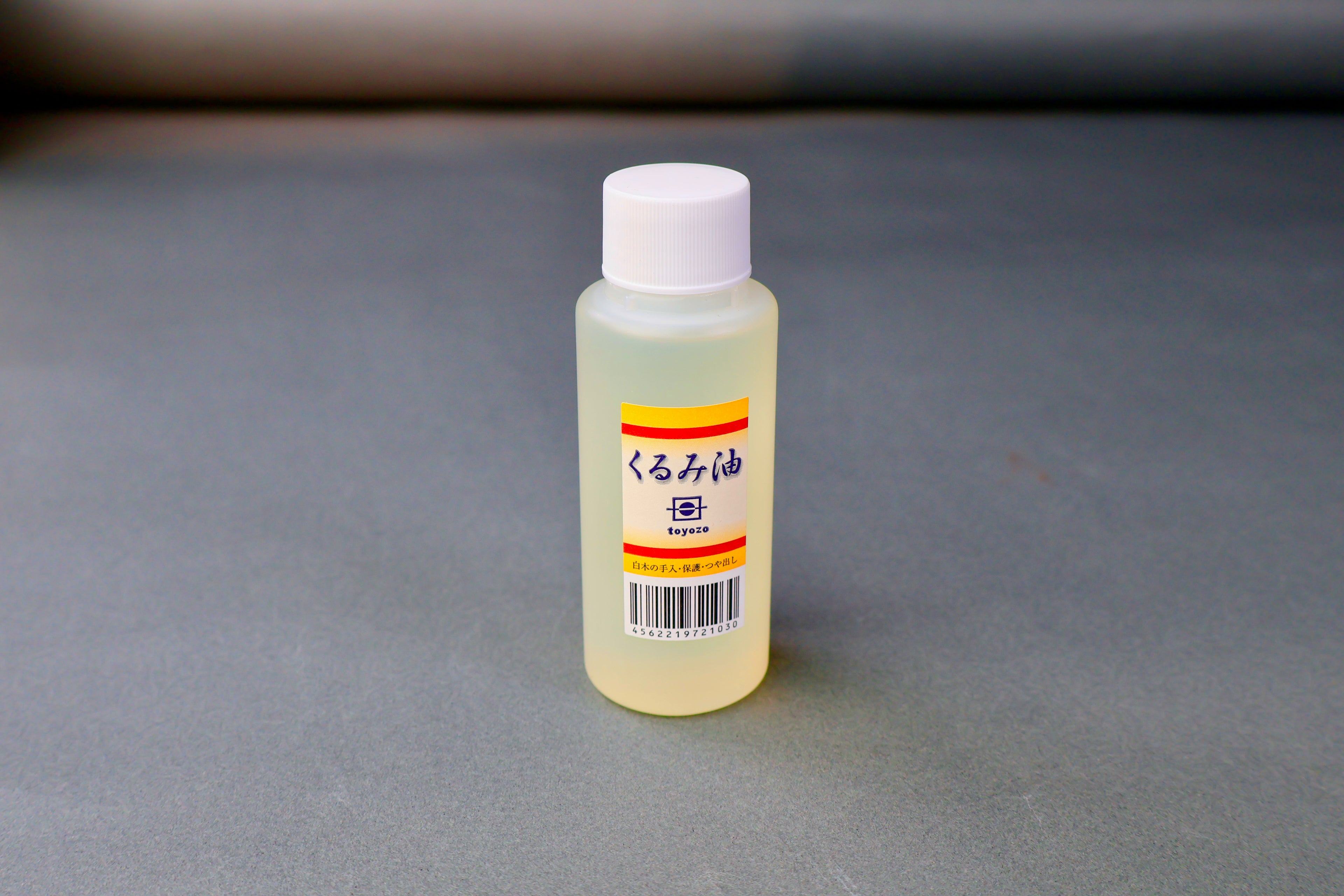 small clear plastic bottle with product label showing yellow and red with hiragana writing in grey background 