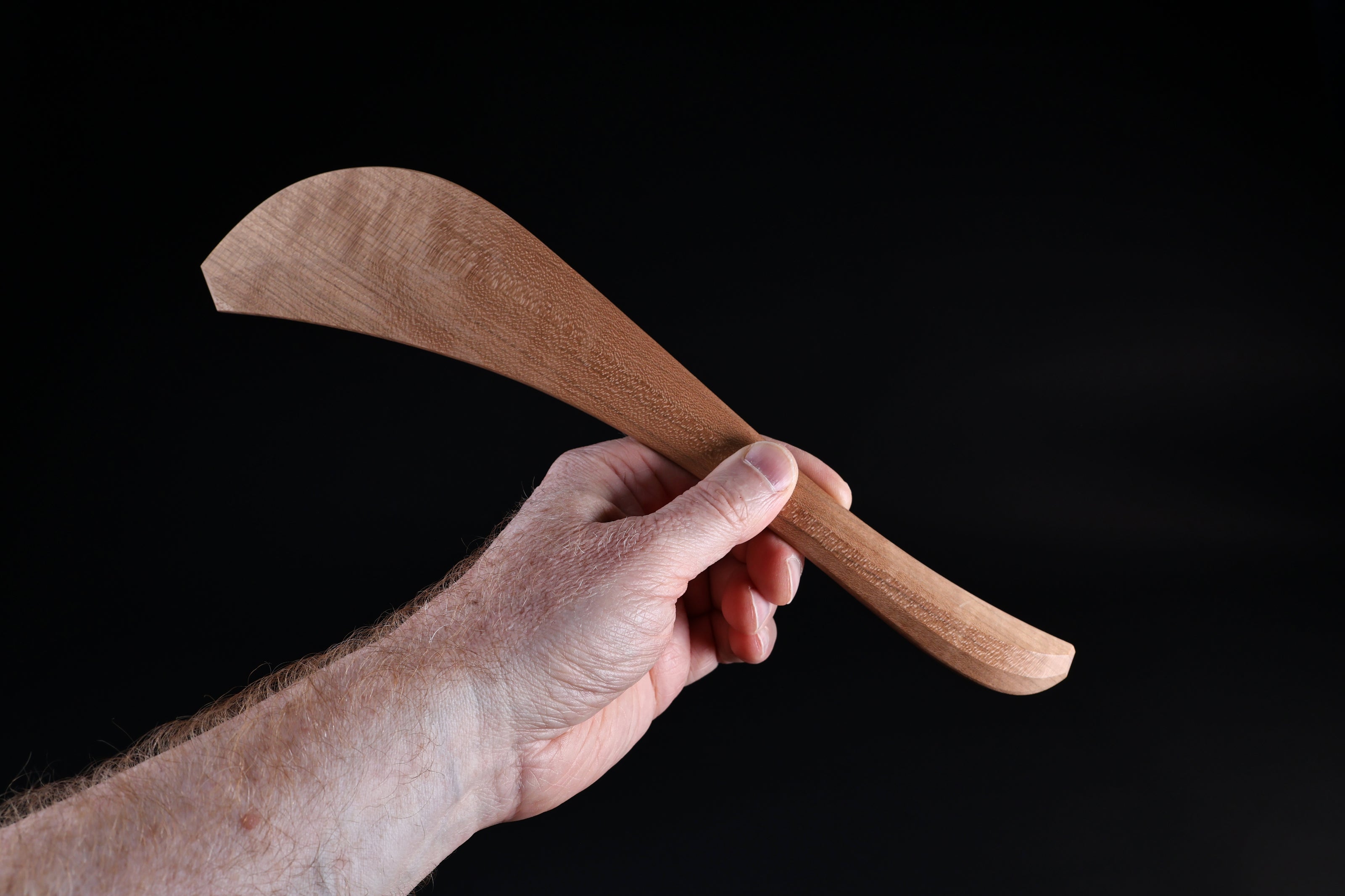 Okubo House cherry wood spatula held upright in hand, showing wide blade shape and curved handle from front