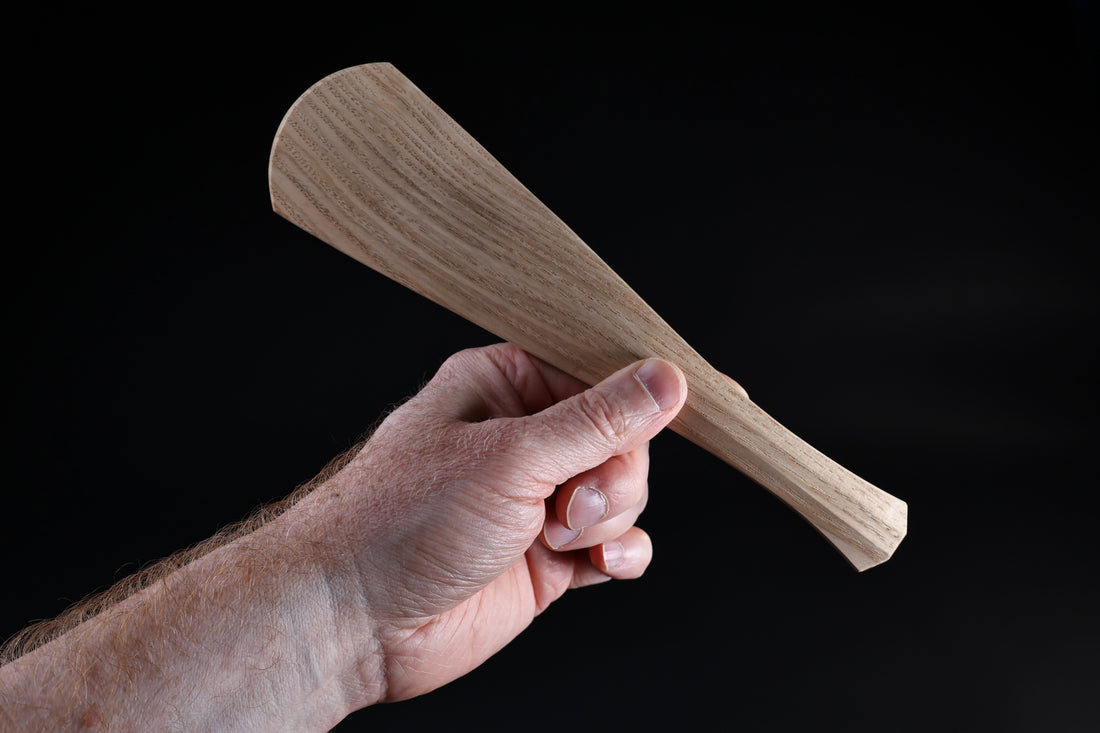 Okubo House chestnut rice paddle — held in hand, paddle end forward showing blade shape and handle construction