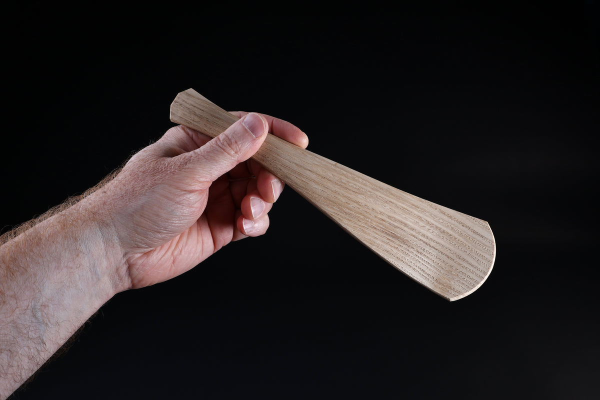 Okubo House chestnut rice paddle — held in hand, paddle face forward showing full form and grain detail