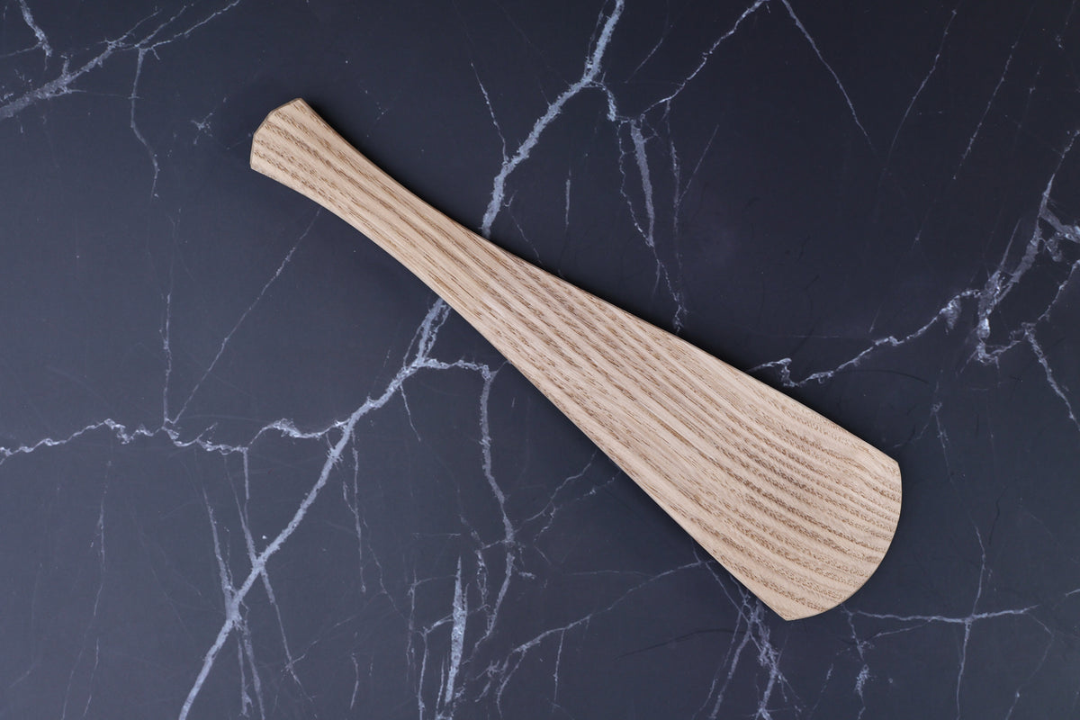 Okubo House chestnut rice paddle — reverse side top view showing ridged grain texture on dark marble surface