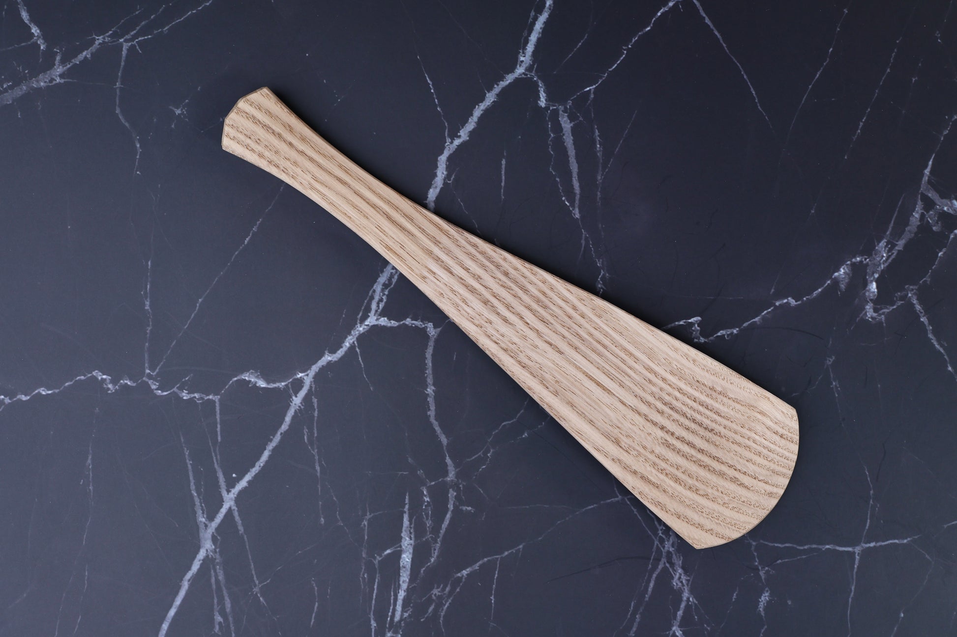 Okubo House chestnut rice paddle — reverse side top view showing ridged grain texture on dark marble surface