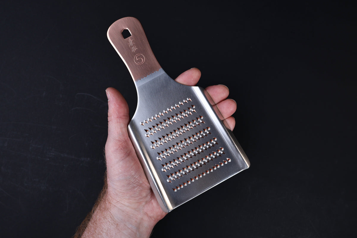 Oroshigane copper grater No. 5 — coarse side held in hand showing tooth pattern and copper handle
