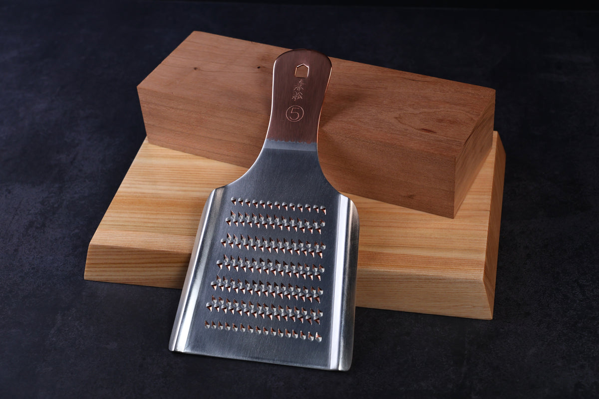 Oroshigane copper grater No. 5 — coarse grating side with maker's mark, propped on hinoki wood blocks