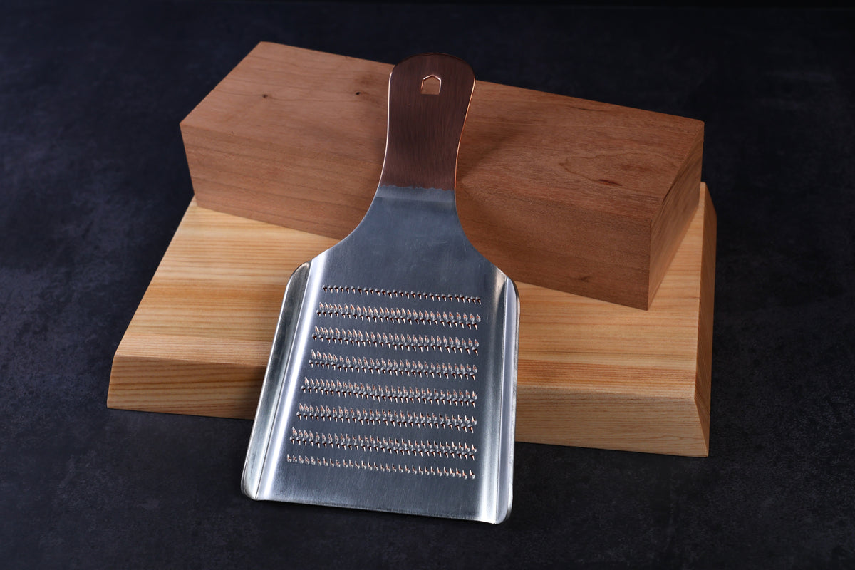 Oroshigane copper grater No. 5 — fine grating side showing smaller tooth pattern, propped on hinoki wood blocks