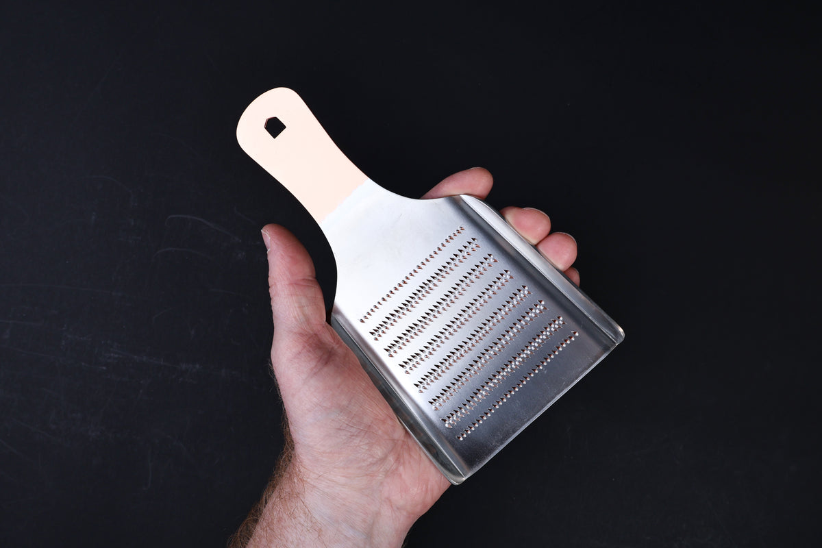Oroshigane copper grater No. 5 — coarse side held in hand showing tooth pattern and copper handle