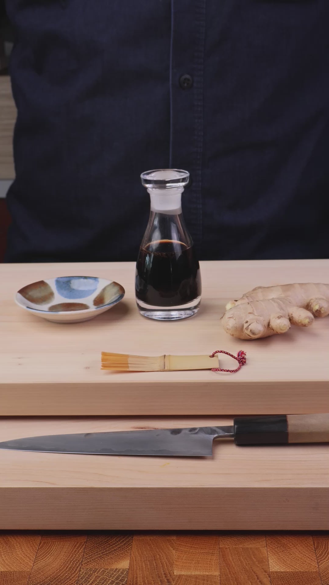 slow motion video showing man hold small dish pouring soy sauce from THE soy sauce cruet crystal glass bottle next man shaking pan with carrots pouring soy sauce into pan 