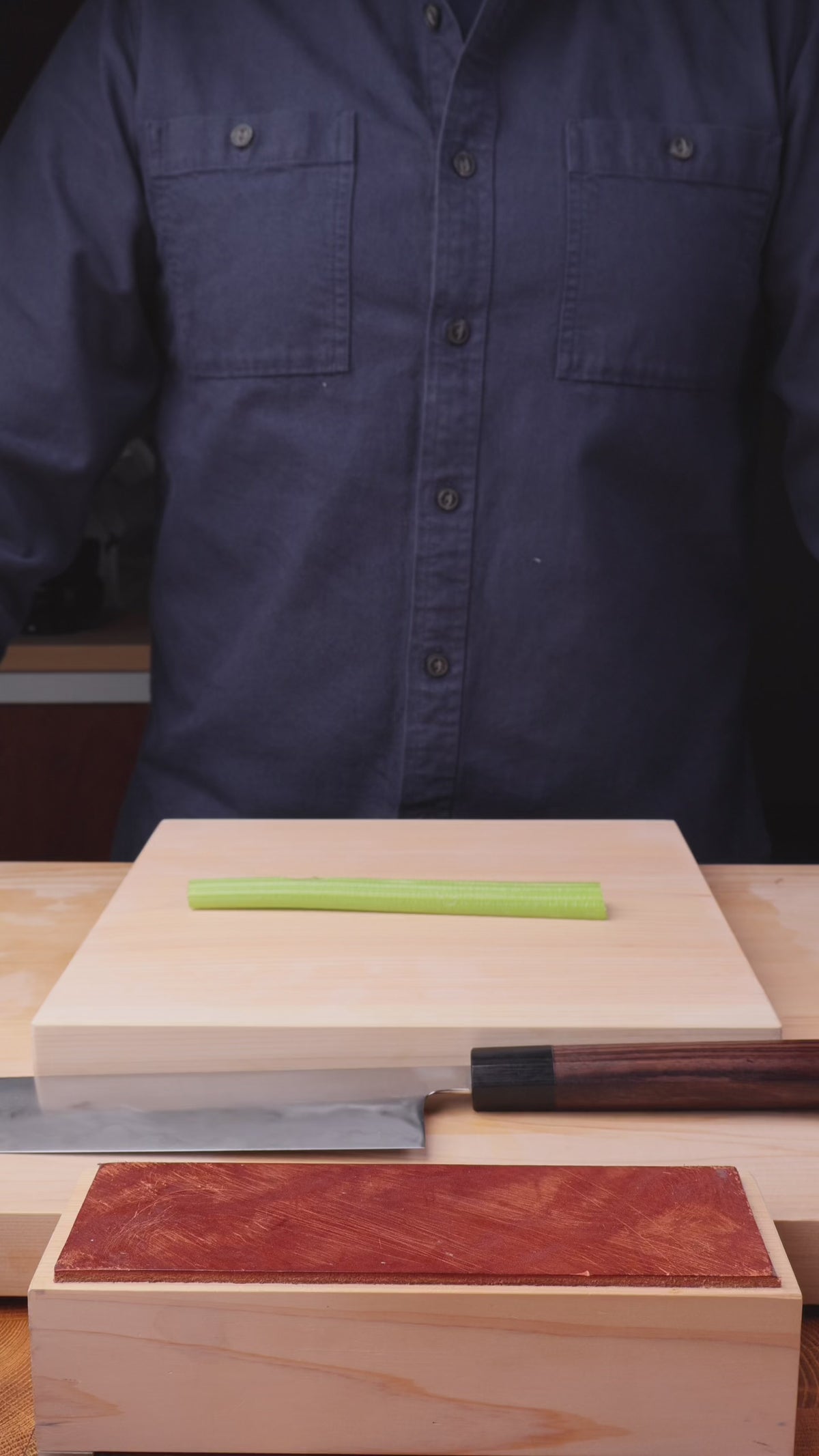 video of man in front of wood cutting and leather strop demonstrating the stropping technique in kitchen background