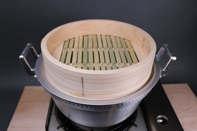 top down view of aluminum pot holding a steam ring and base of hinoki and bamboo steamer 