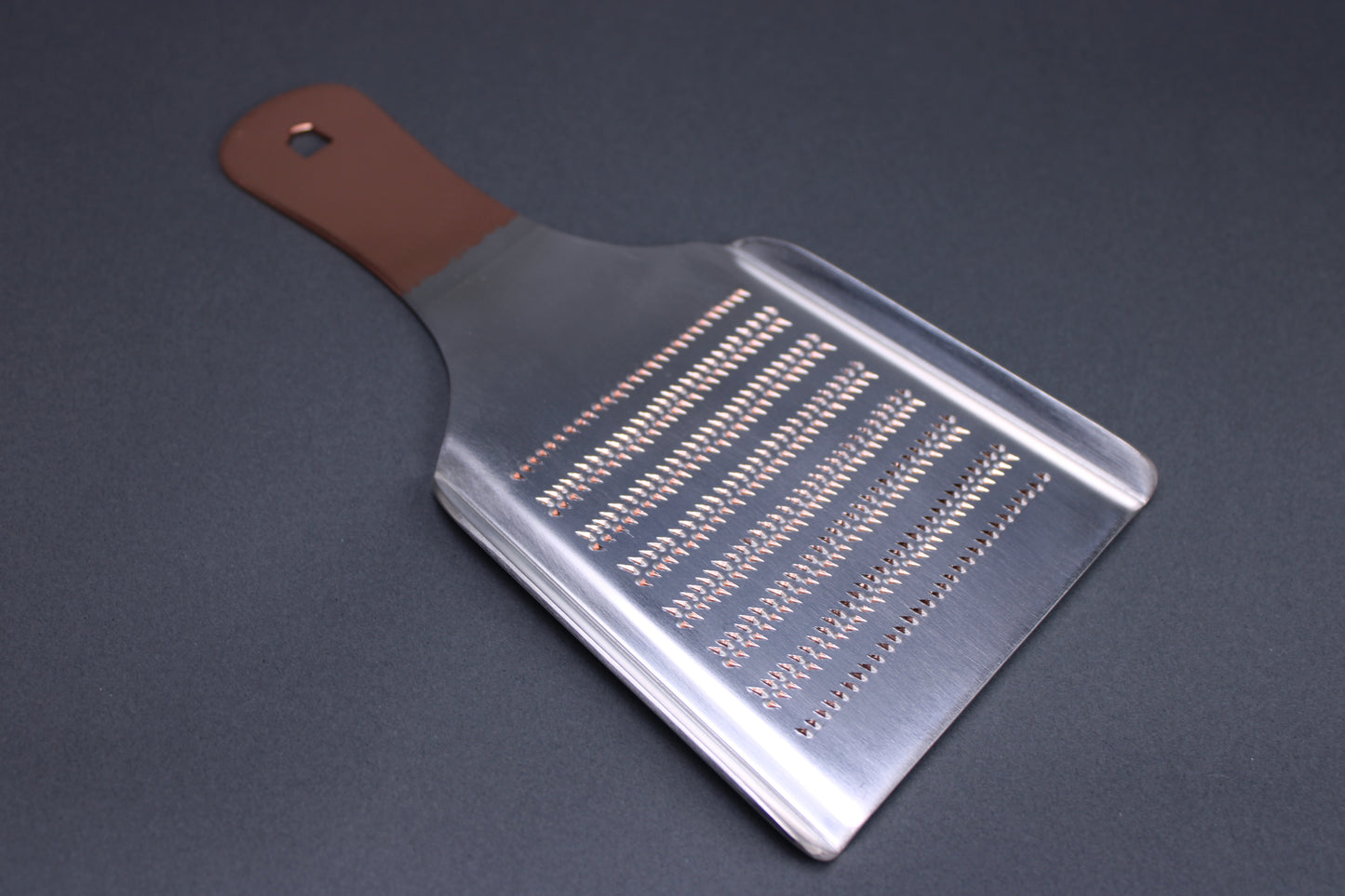  backside shot fine spikes for wasabi grating copper colored handle silver body grey background
