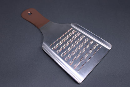  backside shot fine spikes for wasabi grating copper colored handle silver body grey background

