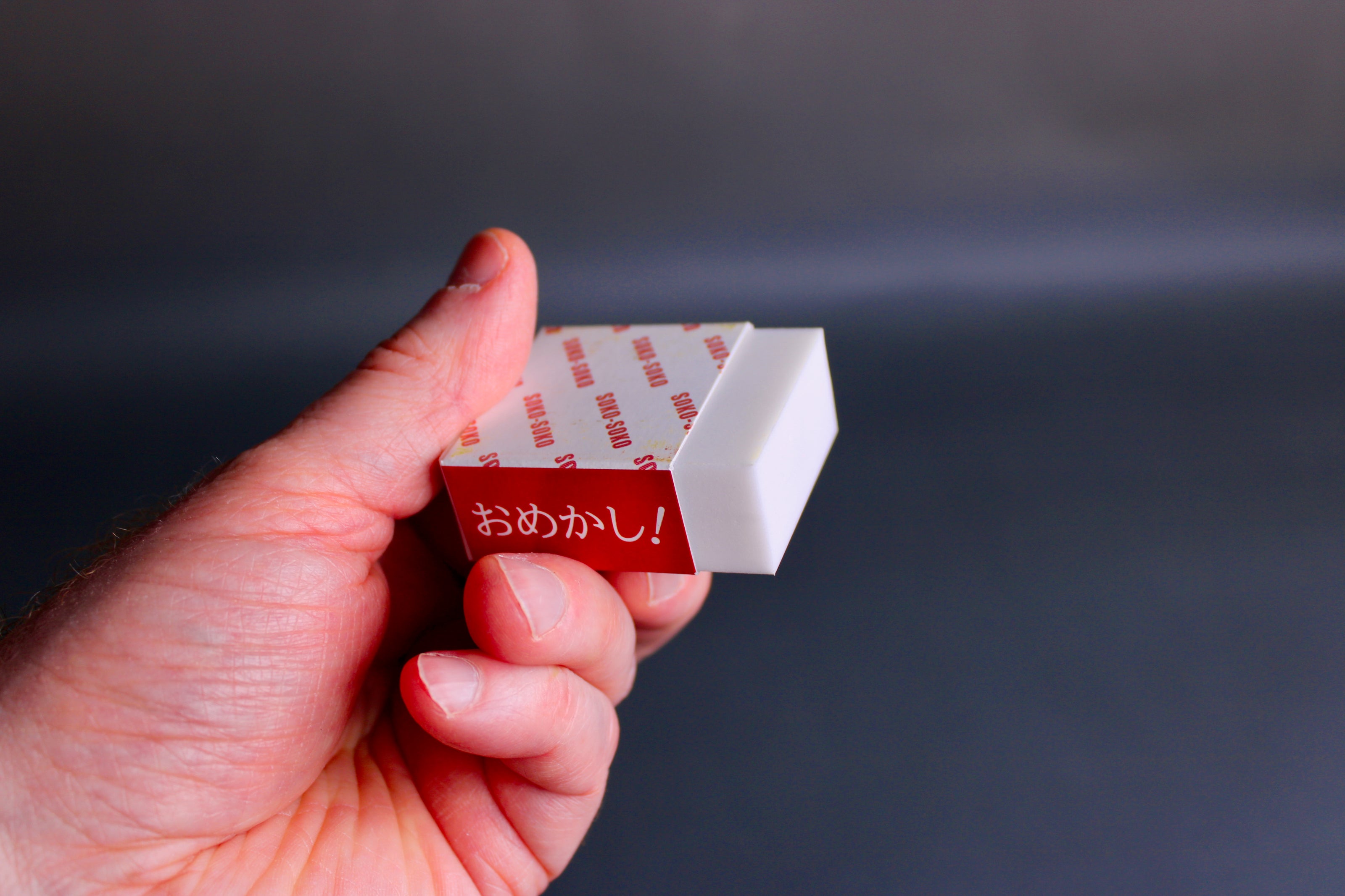 hand holding partially wrapped white rust eraser in grey background