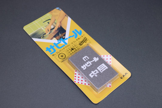 top view rust eraser m sabitoru product in yellow and blue packaging showing person cleaning stovetop with rust eraser grey background

