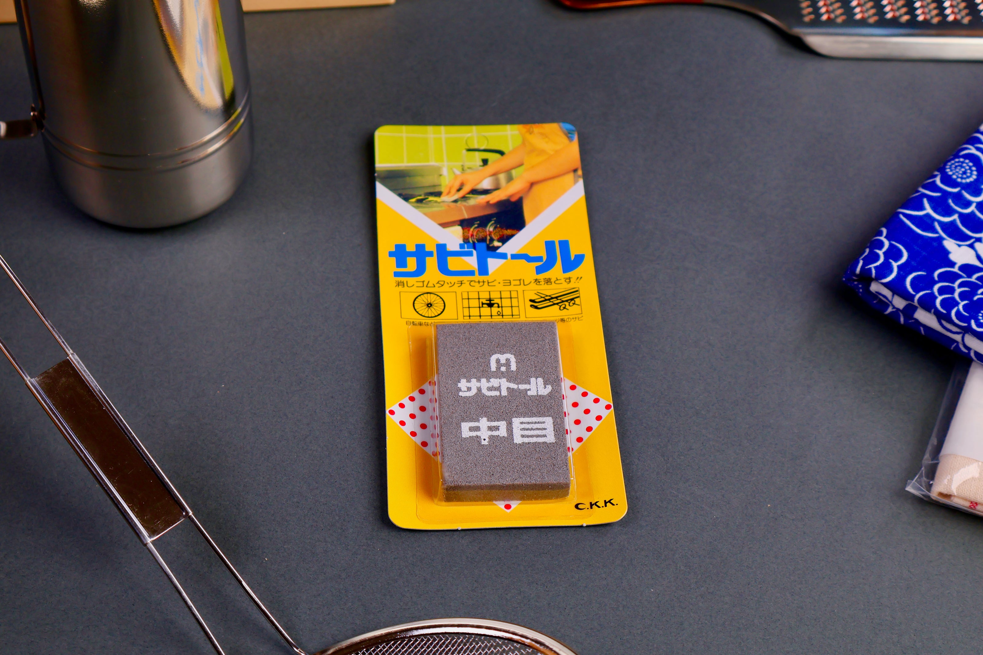 long rectangular package holding smaller rectangular rust eraser with white kanji print next contrasted with bright yellow packaging