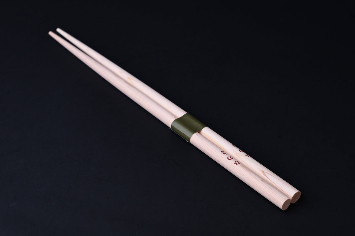 Saibashi round cooking chopsticks — full length angled view, handle end down showing taper and green band