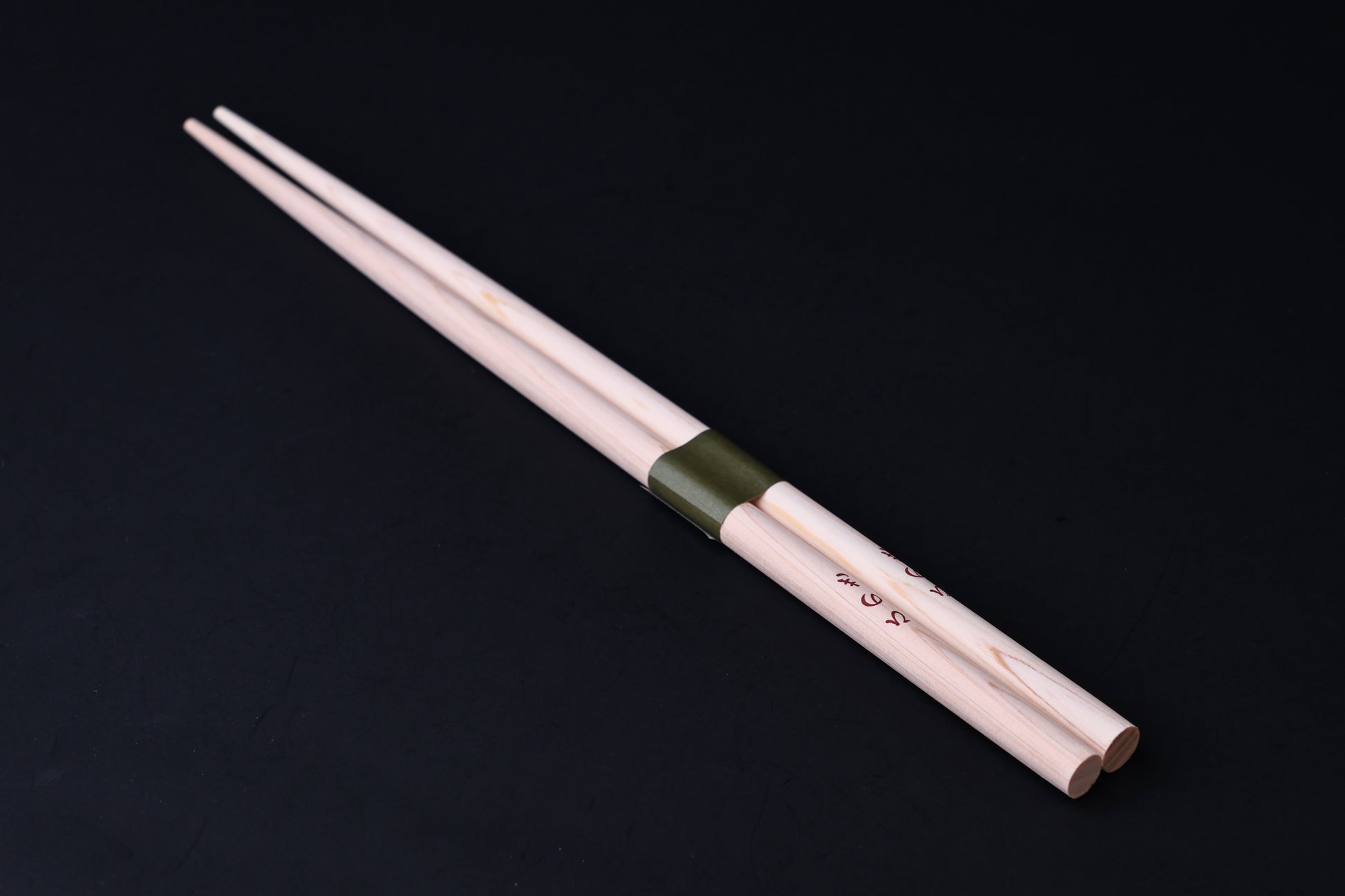 Saibashi round cooking chopsticks — full length angled view, handle end down showing taper and green band