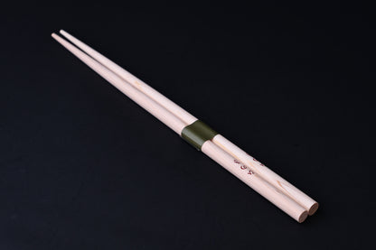 Saibashi round cooking chopsticks — full length angled view, handle end down showing taper and green band