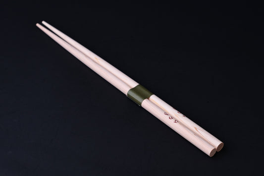 Saibashi round cooking chopsticks — full length angled view, handle end down showing taper and green band