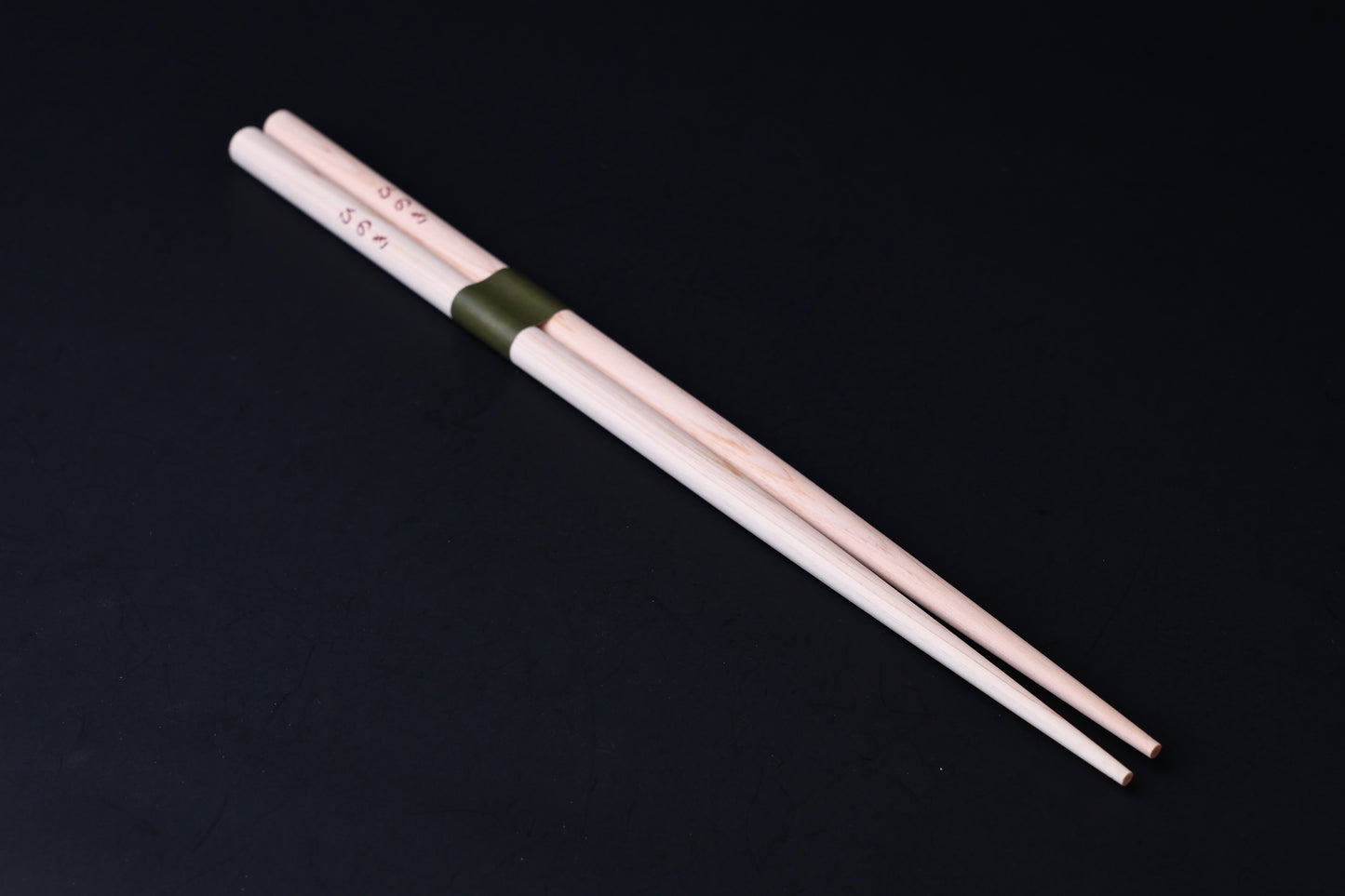 Saibashi round cooking chopsticks — full length angled view, tip end down showing taper and round cross-section