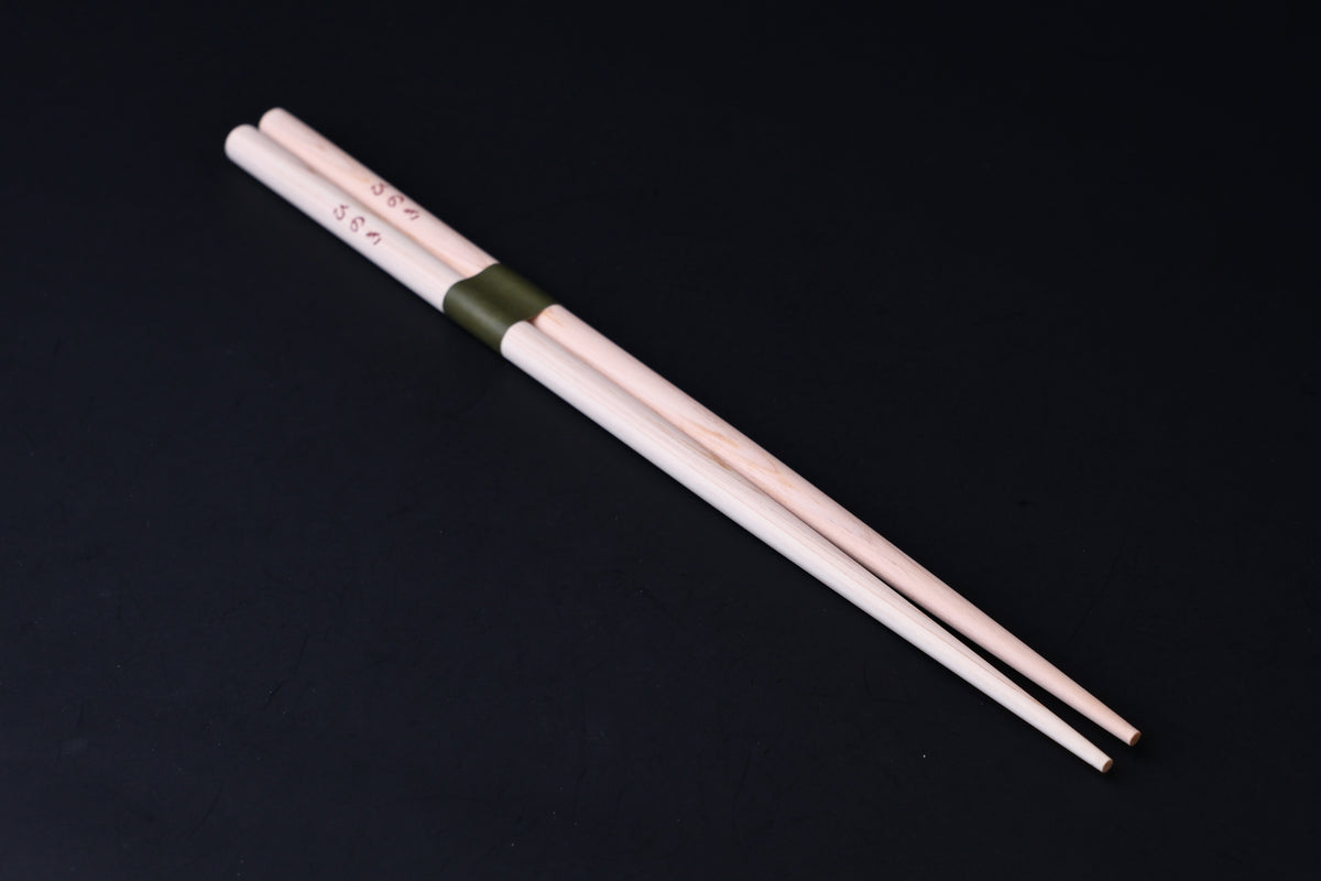 Saibashi round cooking chopsticks — full length angled view, tip end down showing taper and round cross-section