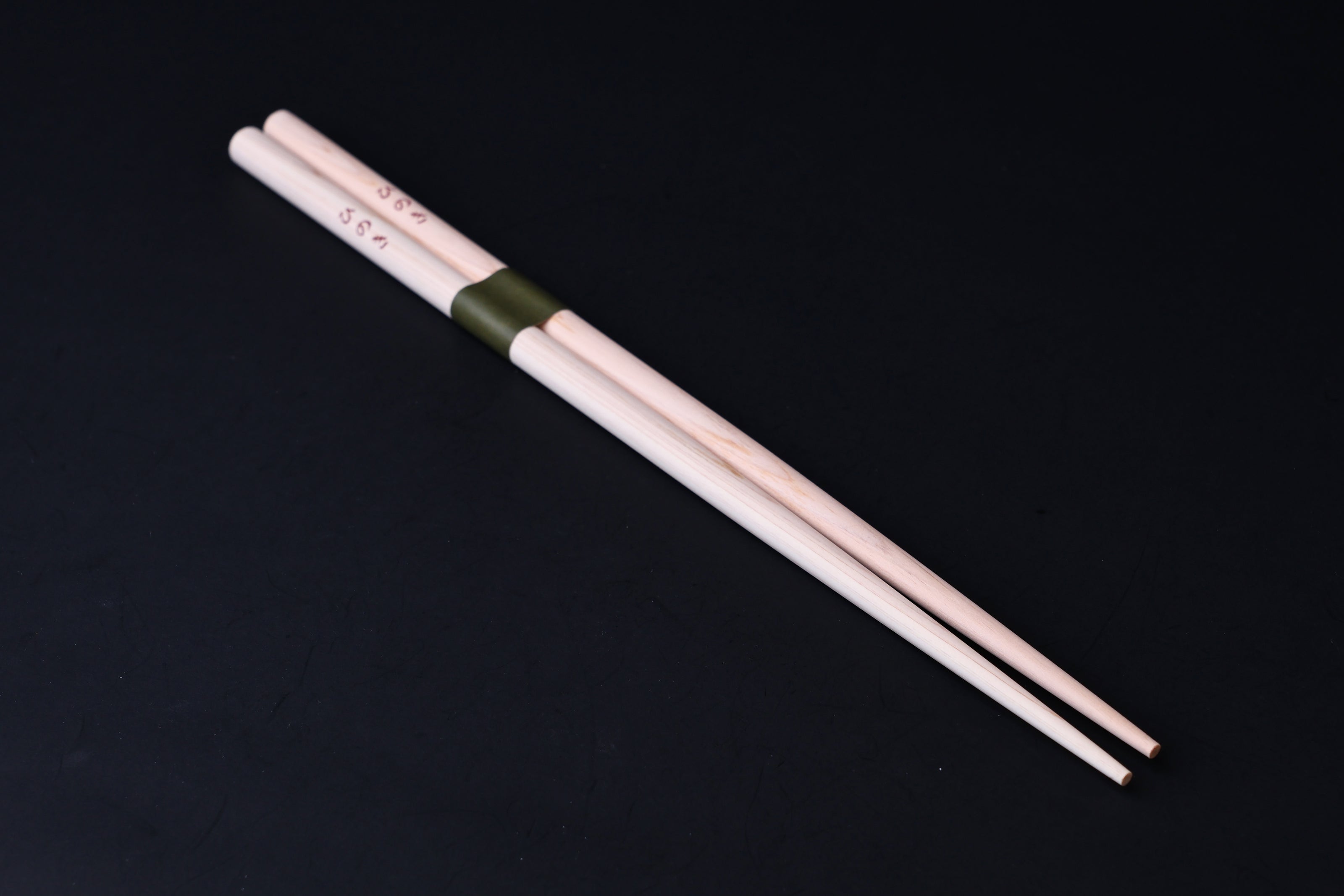 Saibashi round cooking chopsticks — full length angled view, tip end down showing taper and round cross-section