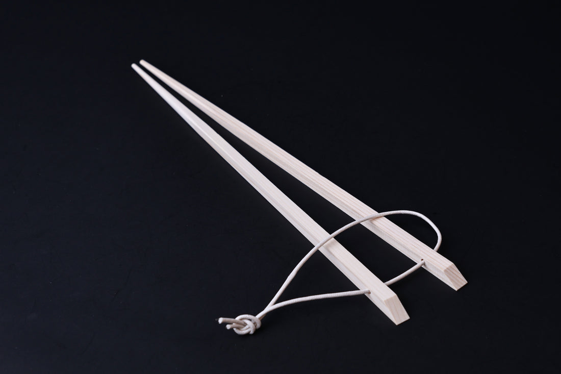 Saibashi square cooking chopsticks — full length angled view, handle end down showing square profile and hanging cord