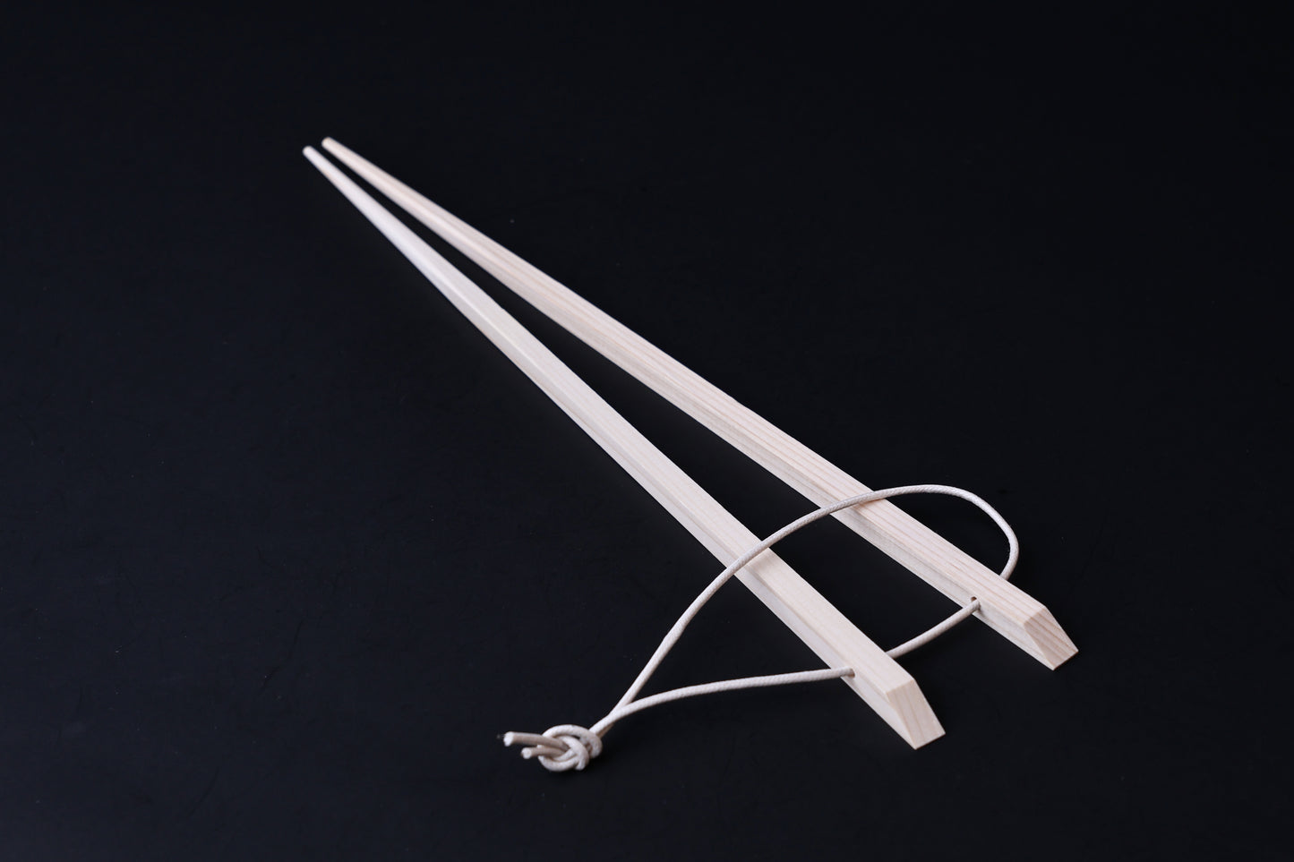 Saibashi square cooking chopsticks — full length angled view, handle end down showing square profile and hanging cord