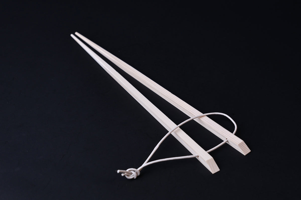 Saibashi square cooking chopsticks — full length angled view, handle end down showing square profile and hanging cord
