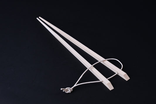 Saibashi square cooking chopsticks — full length angled view, handle end down showing square profile and hanging cord