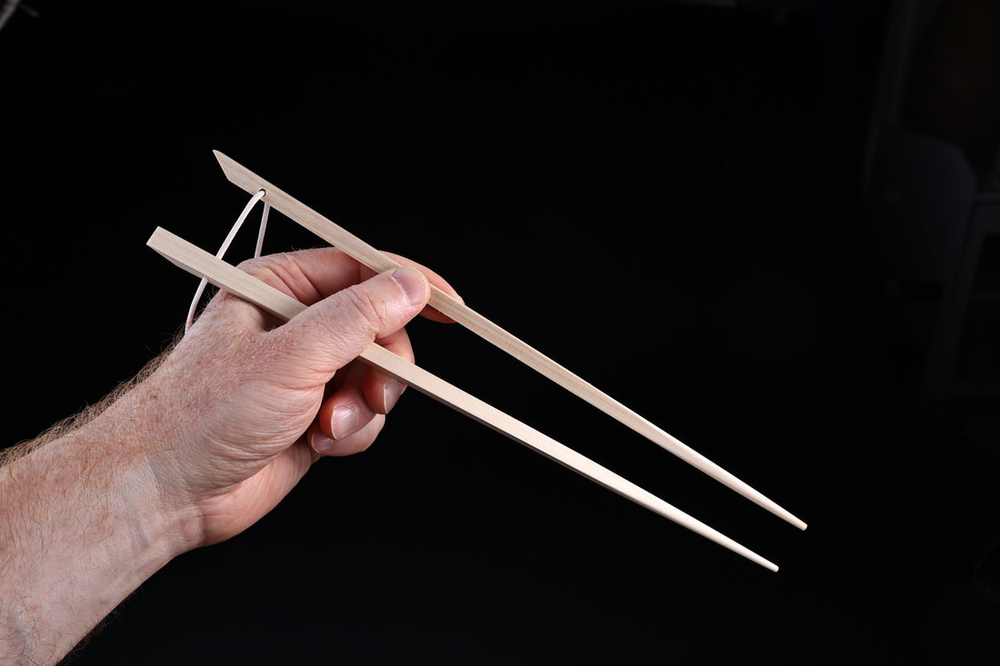Saibashi square cooking chopsticks — held in hand showing grip position and square cross-section profile