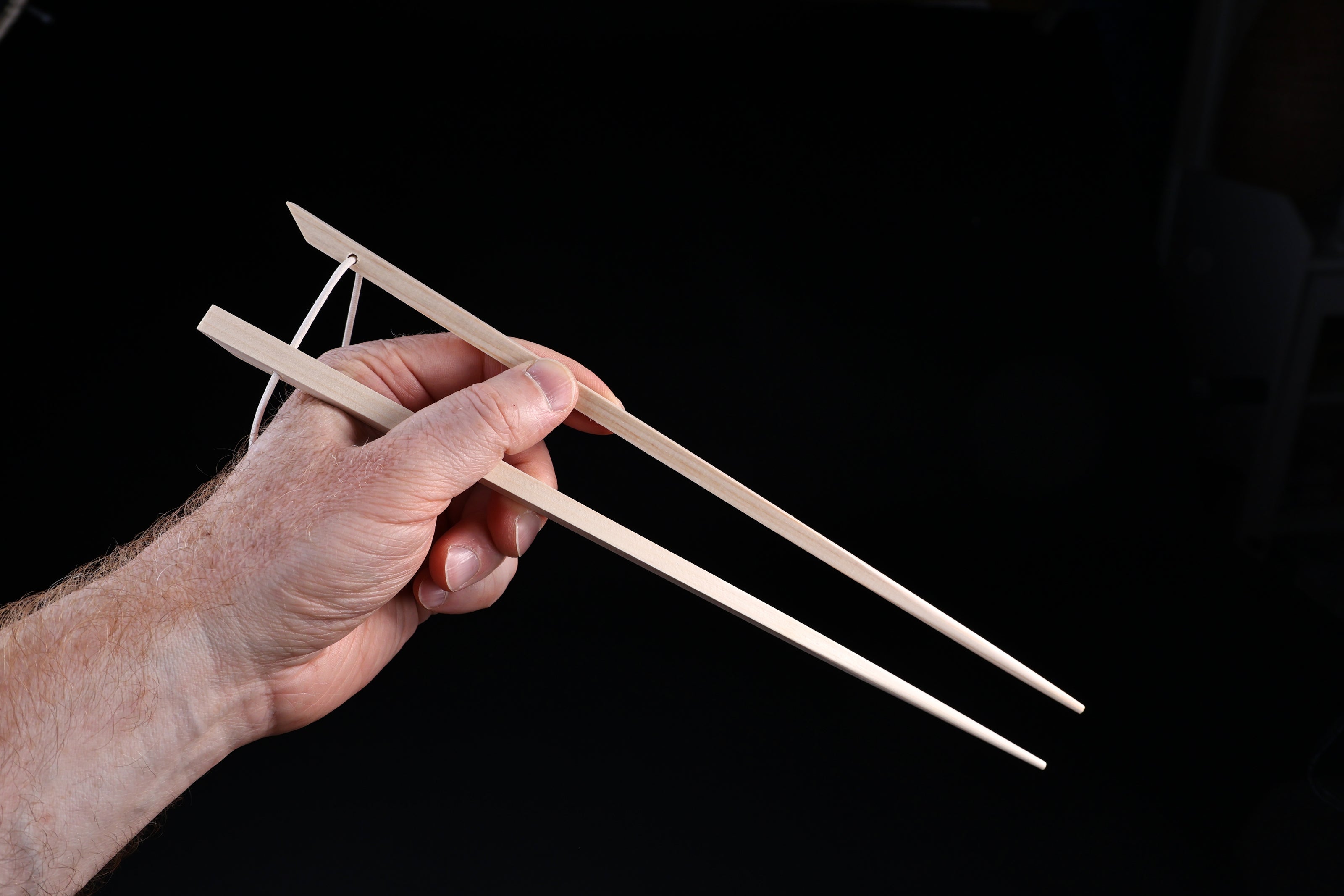 Saibashi square cooking chopsticks — held in hand showing grip position and square cross-section profile