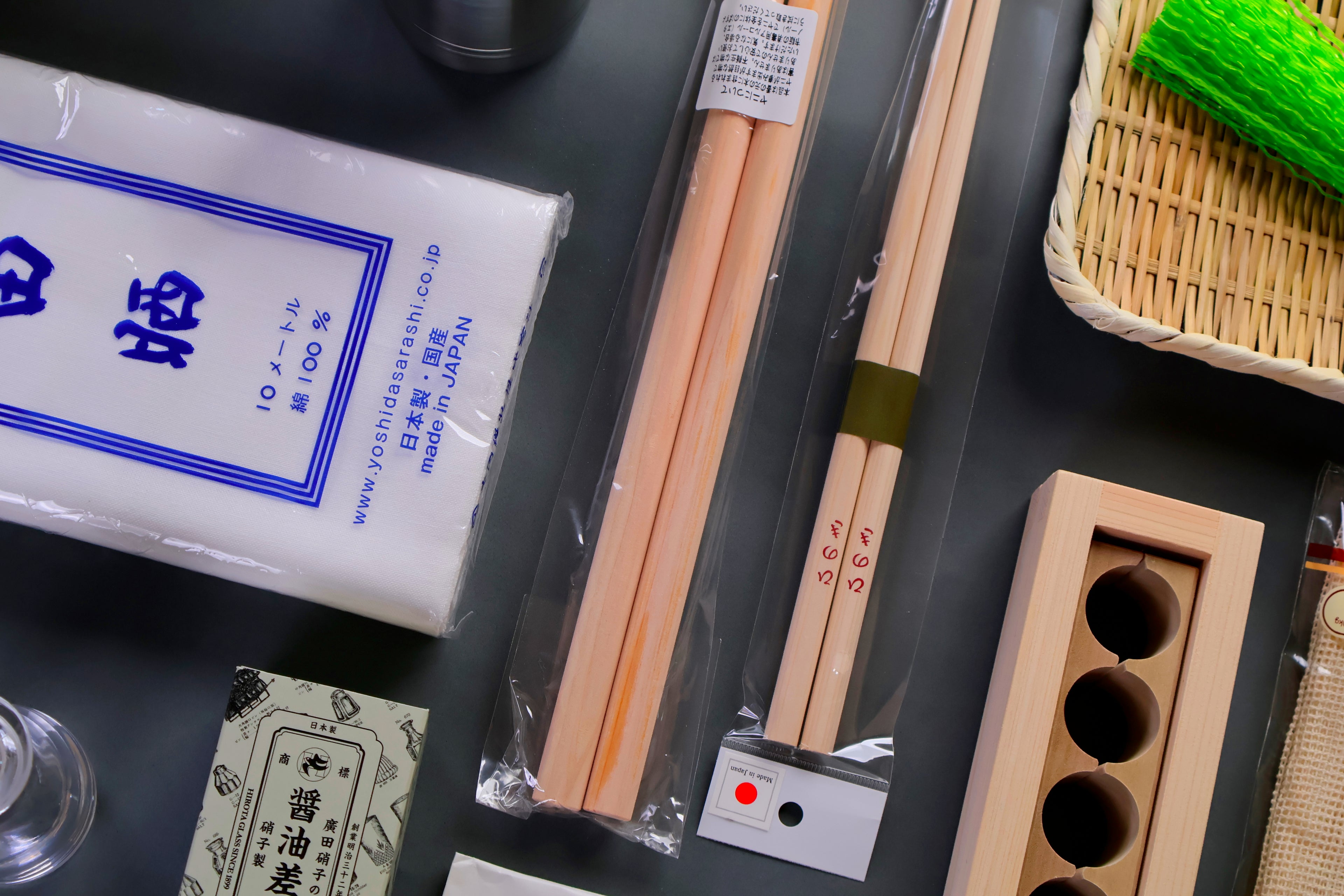 Set of wooden chopsticks with packaging and a wooden holder on a dark surface.