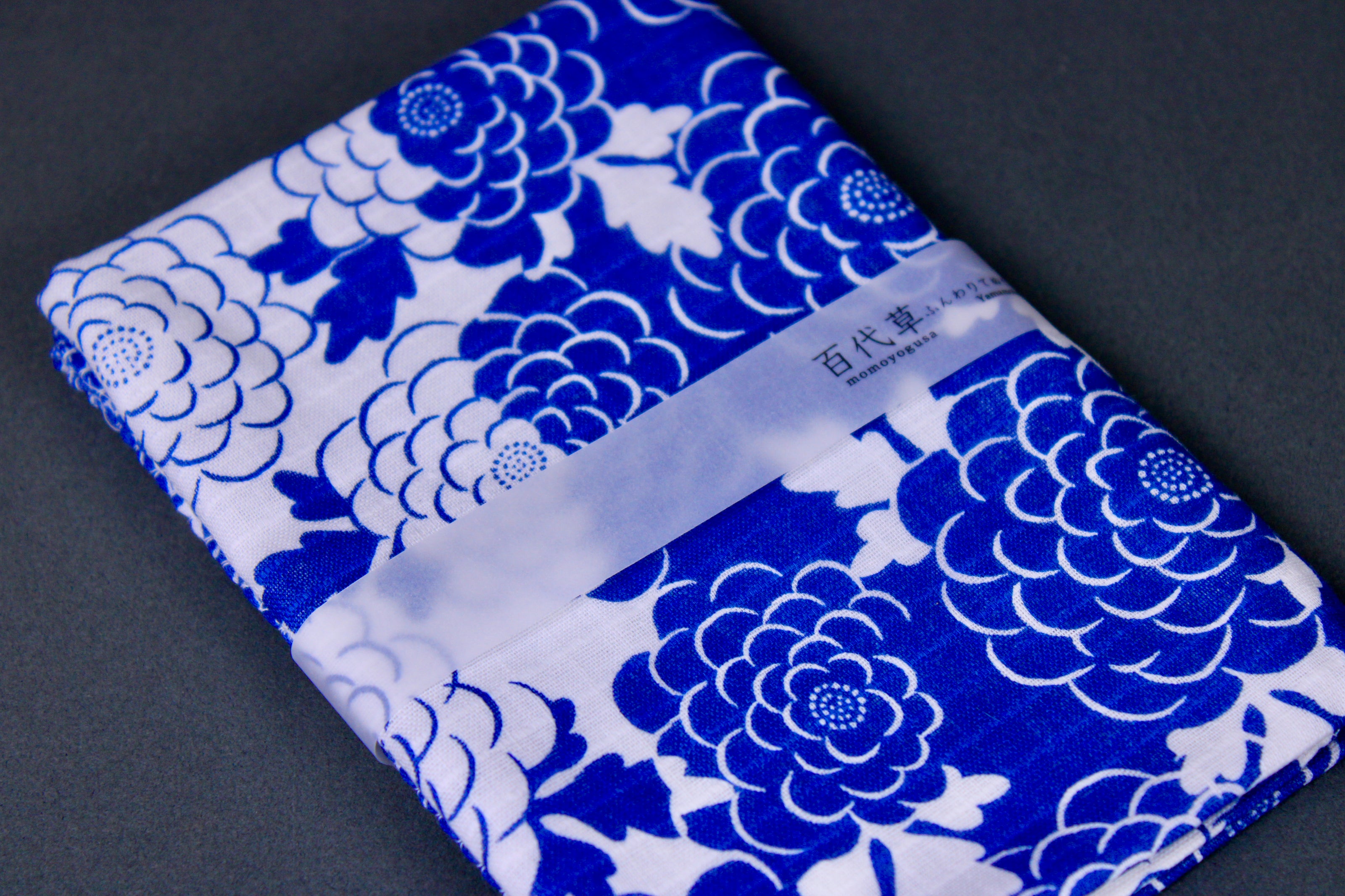 rectangular packaged sarashi towel printed with blue white classic floral pattern on dark backdrop