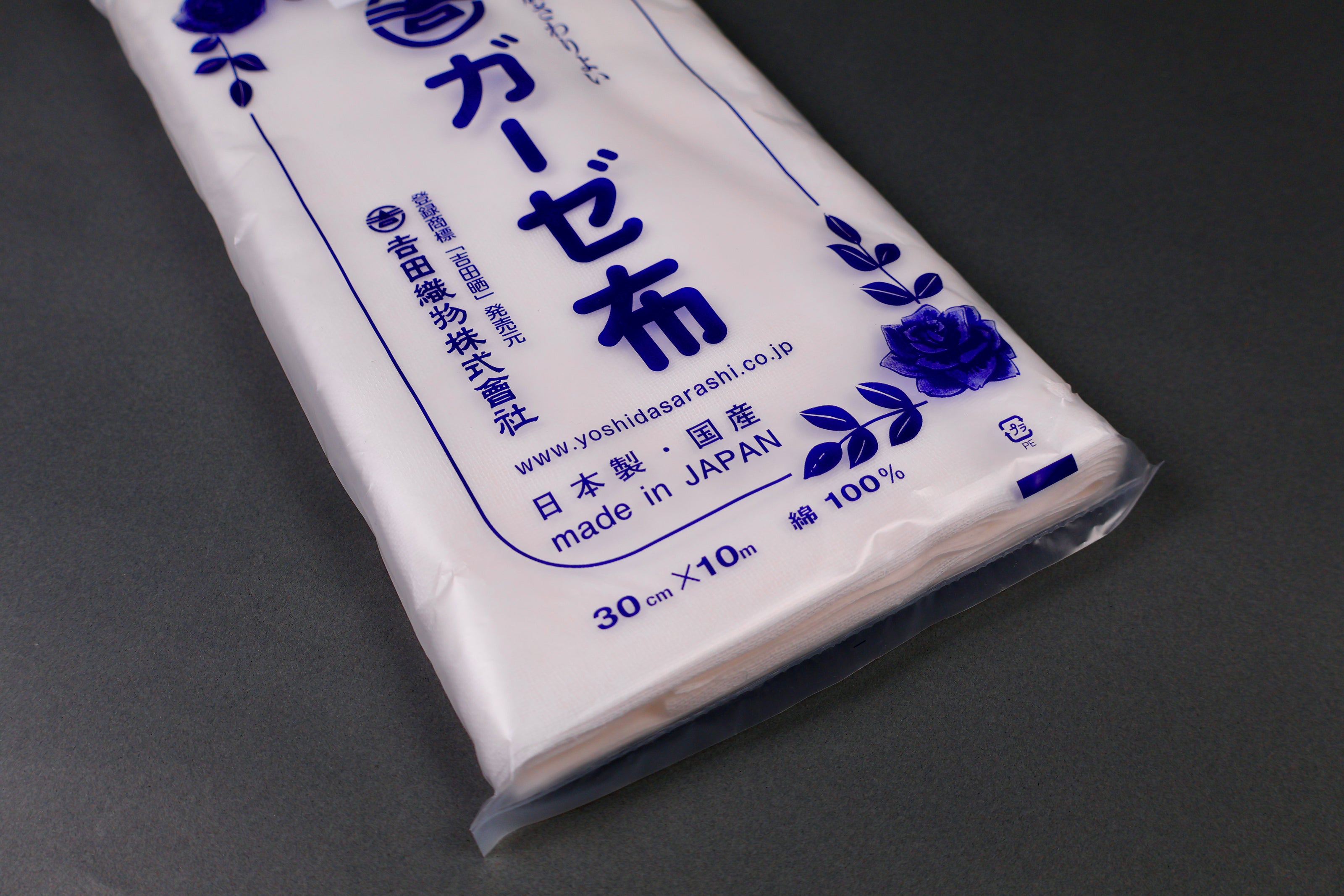clear packaged antibacterial gauze cloth package shows blue print of hiragana and floral pattern on dark grey background