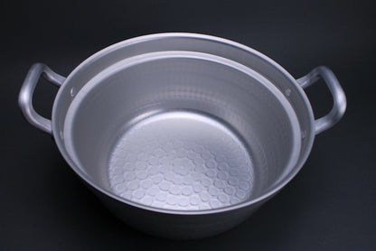 Detail internal shot of dantsuki steaming pot showing stamped surface from hammering excellent heat distribution two handled silver color with grey background