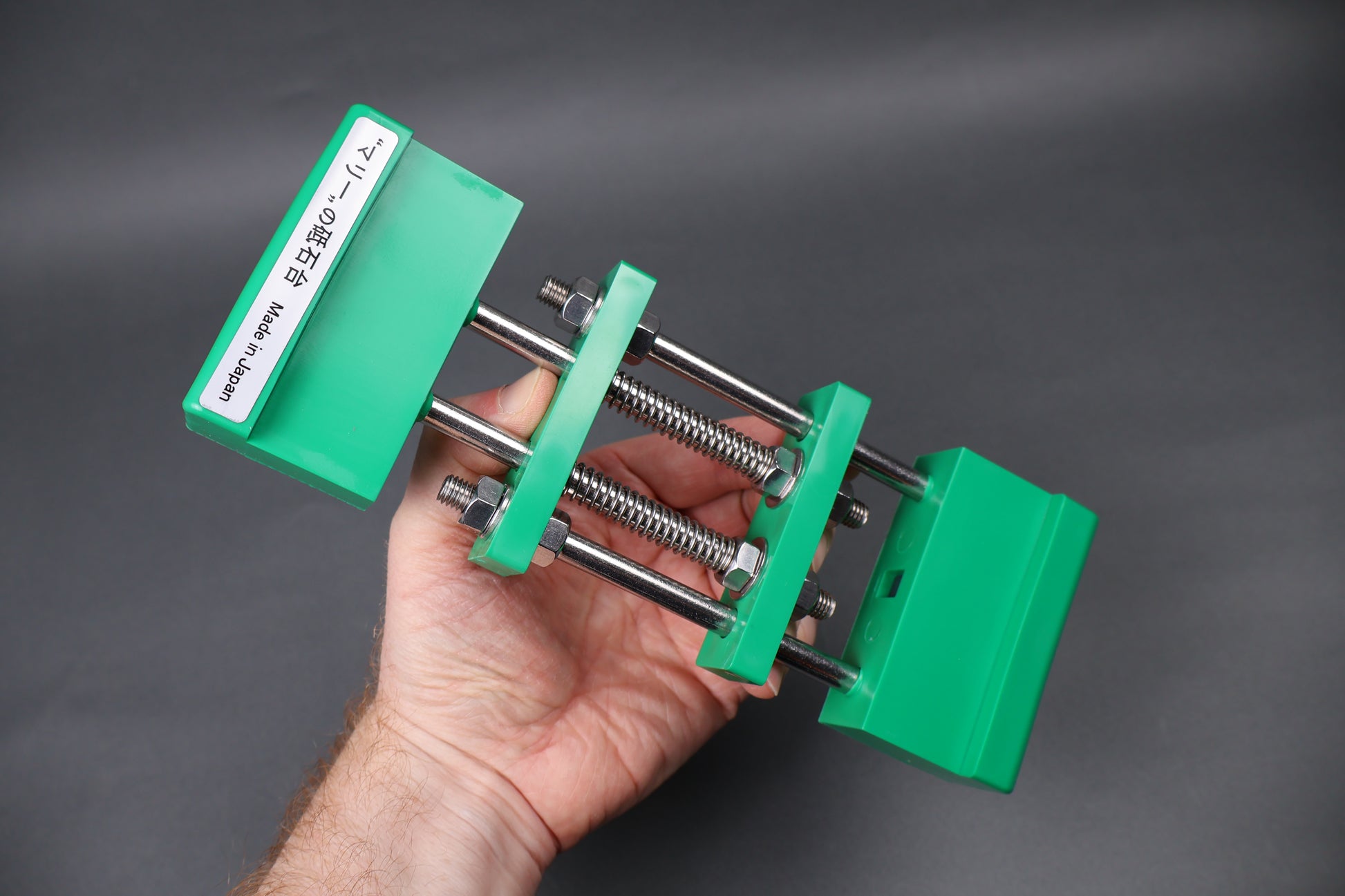 green whetstone holder held in hand at angle grey background