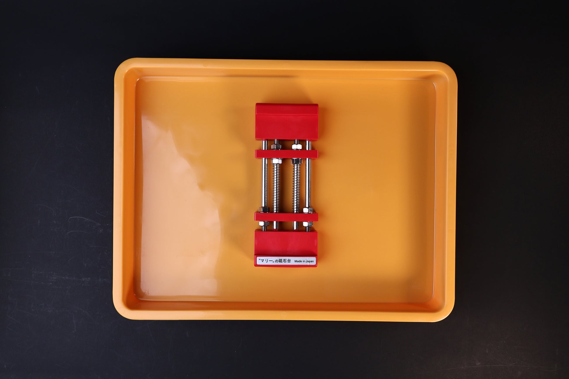 Sharpening Station Kit overhead view — red adjustable whetstone holder centered in orange soaking tray with water