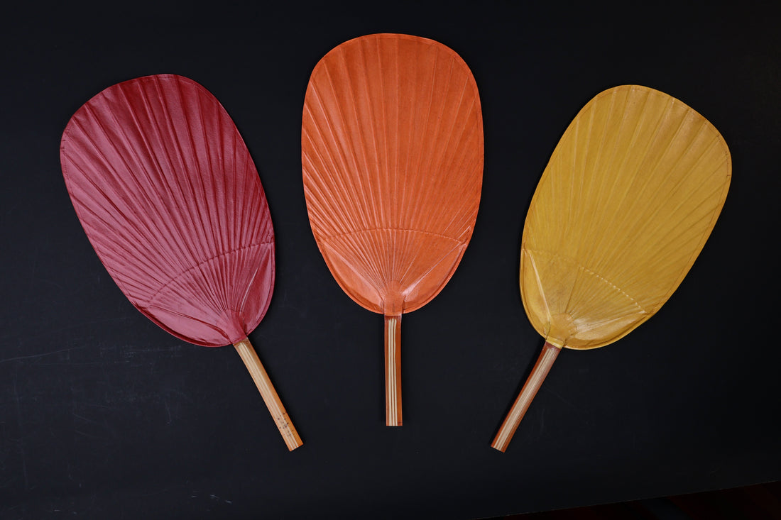 Shibu grilling fan in red, orange, and yellow displayed side by side on black background, showing all three color options