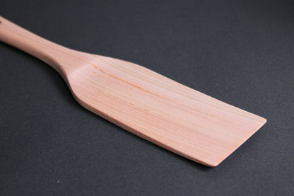 hinoki wood spatula long wide with thin handle and broad spatula area on dark grey surface